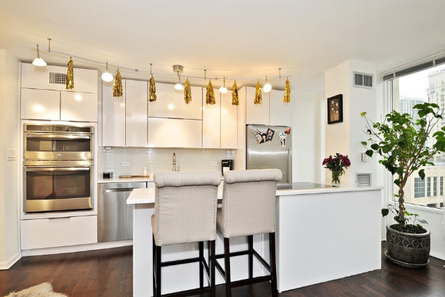 100 E Walton St Unit 22H, Chicago, IL 60611 - kitchen with stainless steel appliances, dark wood-style floors, decorative backsplash, a breakfast bar area, and light countertops