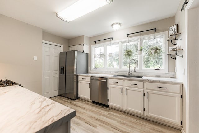 30 Beau Meade Rd, Oswego, IL 60543 - kitchen featuring appliances with stainless steel finishes, a sink, white cabinetry, light wood-style flooring, and healthy amount of natural light