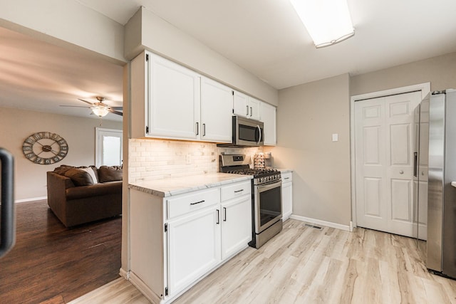 30 Beau Meade Rd, Oswego, IL 60543 - kitchen featuring appliances with stainless steel finishes, light wood-style flooring, decorative backsplash, white cabinets, and ceiling fan