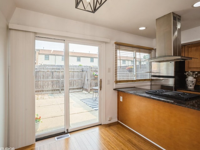 1812 Bristol Walk Unit 1812, Hoffman Estates, IL 60169 - kitchen featuring island exhaust hood, light wood-type flooring, black gas stovetop, brown cabinetry, and baseboards