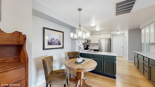 5400 Walnut Ave Unit 201, Downers Grove, IL 60515 - kitchen with stainless steel appliances, backsplash, light countertops, light wood-style floors, and white cabinetry