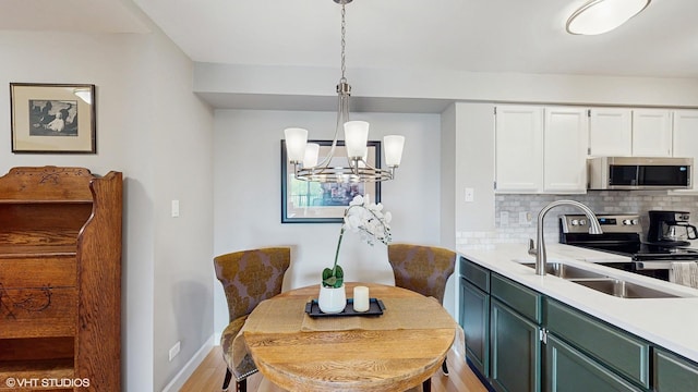 5400 Walnut Ave Unit 201, Downers Grove, IL 60515 - kitchen with stainless steel appliances, a chandelier, decorative backsplash, white cabinetry, and light countertops
