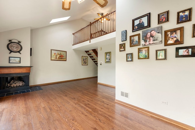 3072 Carlton Ct, Westchester, IL 60154 - unfurnished living room with ceiling fan, wood finished floors, high vaulted ceiling, a skylight, and stairs