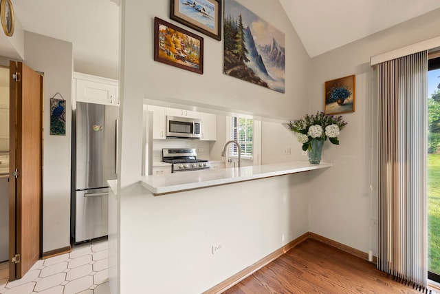 3072 Carlton Ct, Westchester, IL 60154 - kitchen with appliances with stainless steel finishes, a peninsula, light countertops, white cabinetry, and lofted ceiling
