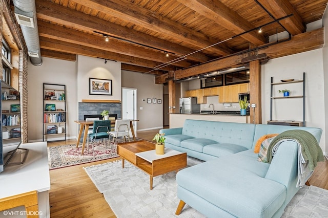 1735 W Diversey Pkwy Unit 402, Chicago, IL 60614 - living room with rail lighting, wood ceiling with exposed beams, light wood finished floors, baseboards, and a fireplace