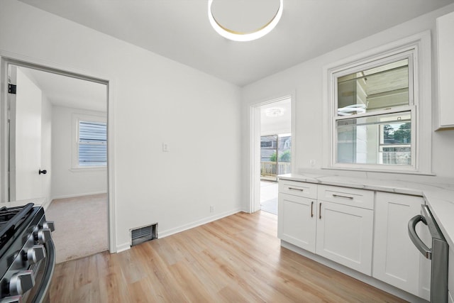 3633 N Lotus Ave, Chicago, IL 60641 - kitchen with gas range oven, dishwasher, light stone countertops, white cabinetry, and light wood-style floors