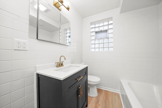 3633 N Lotus Ave, Chicago, IL 60641 - bathroom with tile walls, vanity, a bathtub, and wood finished floors