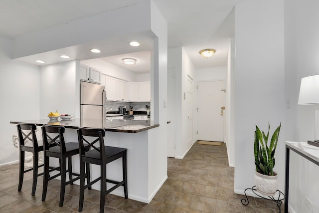 1550 N Lake Shore Dr Unit 9F, Chicago, IL 60610 - kitchen with freestanding refrigerator, a breakfast bar area, baseboards, white cabinets, and decorative backsplash