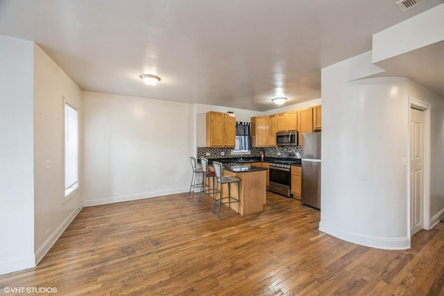 805 S Independence Blvd Unit 3, Chicago, IL 60624 - kitchen featuring appliances with stainless steel finishes, a breakfast bar area, wood finished floors, and dark countertops