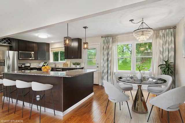 354 W Pleasant Hill Blvd, Palatine, IL 60067 - kitchen with stainless steel appliances, dark wood-style floors, a breakfast bar, light stone countertops, and a chandelier