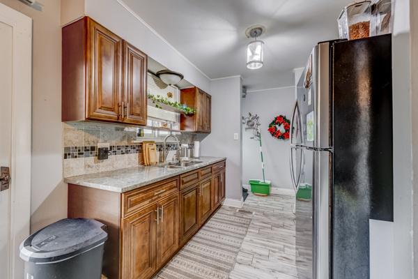 426 Greentree Ln, Bolingbrook, IL 60440 - kitchen with freestanding refrigerator, a sink, backsplash, brown cabinetry, and baseboards