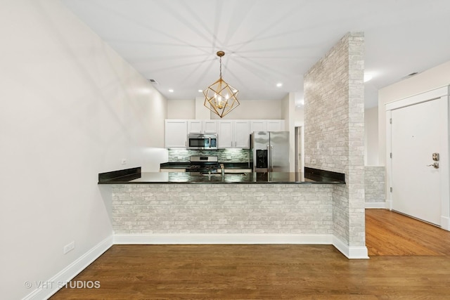 23 N Racine Ave Unit 405, Chicago, IL 60607 - kitchen featuring appliances with stainless steel finishes, a peninsula, wood finished floors, a chandelier, and decorative light fixtures