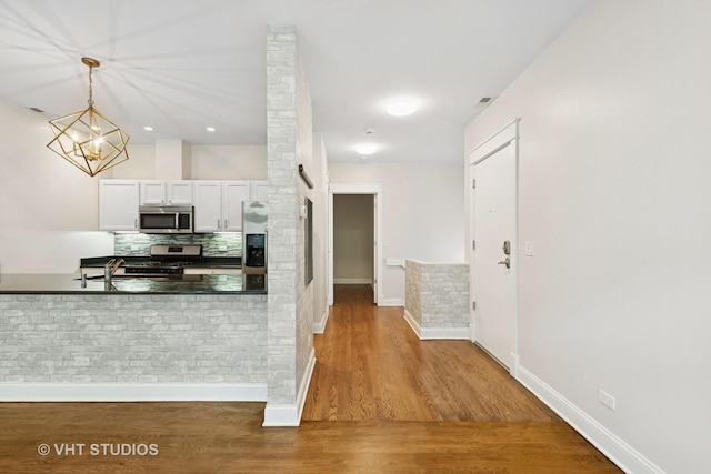 23 N Racine Ave Unit 405, Chicago, IL 60607 - kitchen featuring stainless steel appliances, tasteful backsplash, wood finished floors, white cabinetry, and decorative light fixtures