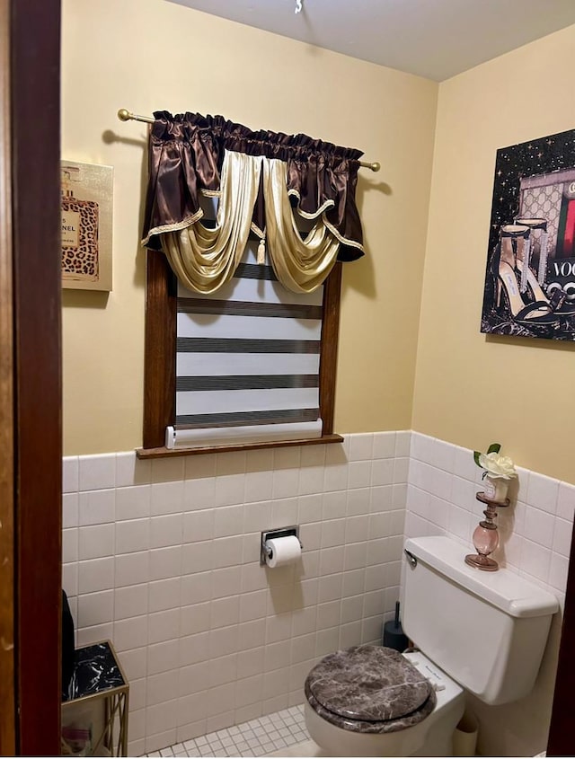 bathroom featuring tile walls, toilet, and wainscoting