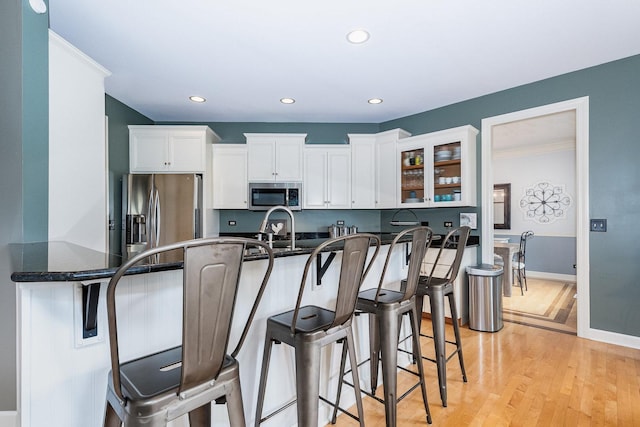 769 Brighton Dr, Sugar Grove, IL 60554 - kitchen with stainless steel appliances, a kitchen breakfast bar, white cabinetry, light wood-type flooring, and glass insert cabinets