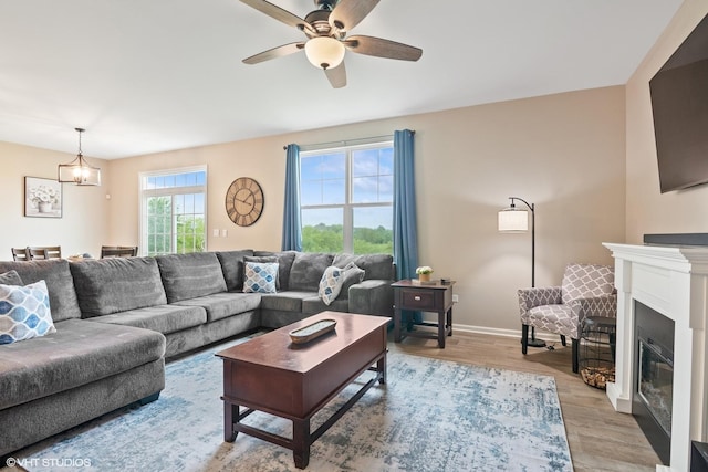 25354 W Cerena Cir, Plainfield, IL 60586 - living area featuring light wood-style flooring, a glass covered fireplace, a ceiling fan, and baseboards