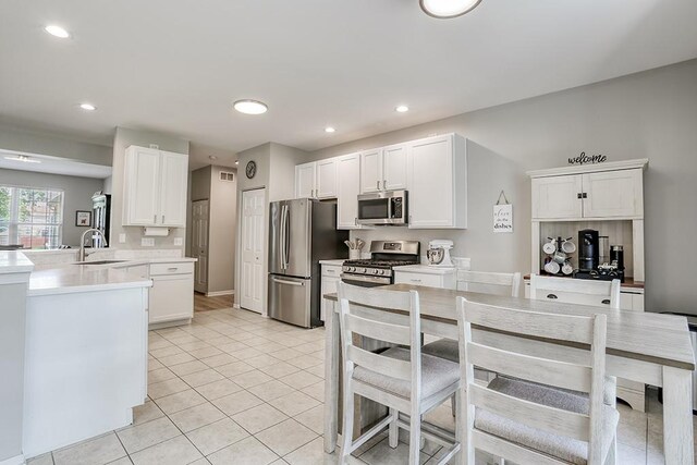 11316 Maplewood Dr, Plainfield, IL 60585 - kitchen with appliances with stainless steel finishes, a peninsula, white cabinetry, light tile patterned flooring, and recessed lighting