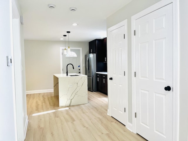 3431 N Kostner Ave, Chicago, IL 60641 - kitchen with freestanding refrigerator, a sink, dark cabinets, light wood-style flooring, and an island with sink