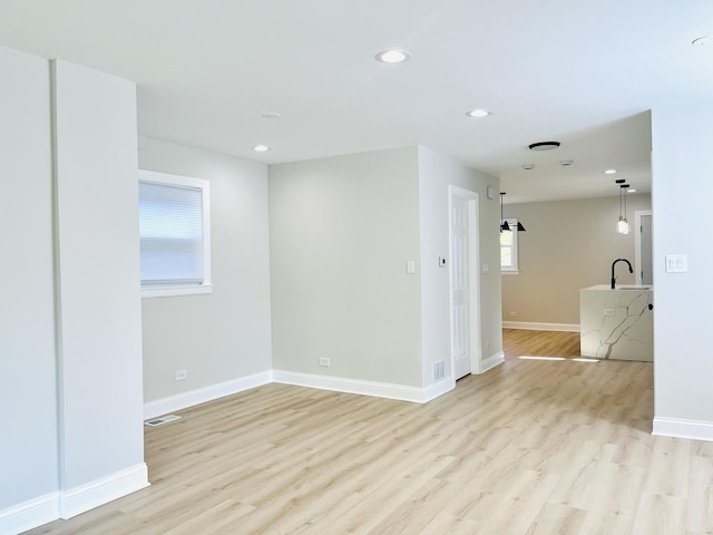 3431 N Kostner Ave, Chicago, IL 60641 - empty room featuring light wood finished floors, recessed lighting, baseboards, and a sink
