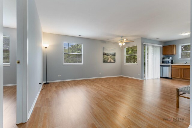 557 E Shag Bark Ln Unit H, Streamwood, IL 60107 - unfurnished living room featuring light wood-style floors, a sink, healthy amount of natural light, and a ceiling fan