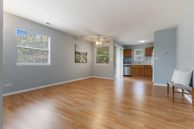 557 E Shag Bark Ln Unit H, Streamwood, IL 60107 - unfurnished living room with light wood-style flooring, a ceiling fan, baseboards, and a sink