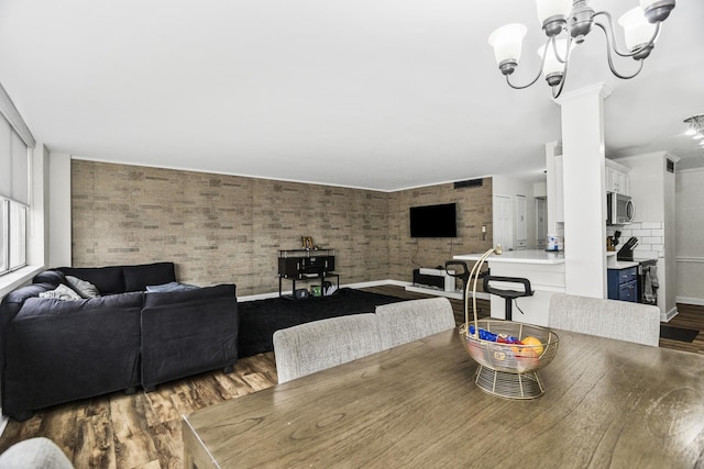 6301 N Sheridan Rd Unit 18E, Chicago, IL 60660 - dining area featuring dark wood finished floors, a chandelier, and brick wall