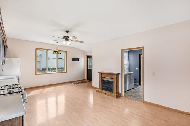 9014 Alden Rd, Harvard, IL 60033 - unfurnished living room featuring ceiling fan, washer and dryer, light wood finished floors, and a glass covered fireplace