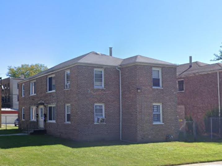 view of side of property featuring a lawn and brick siding