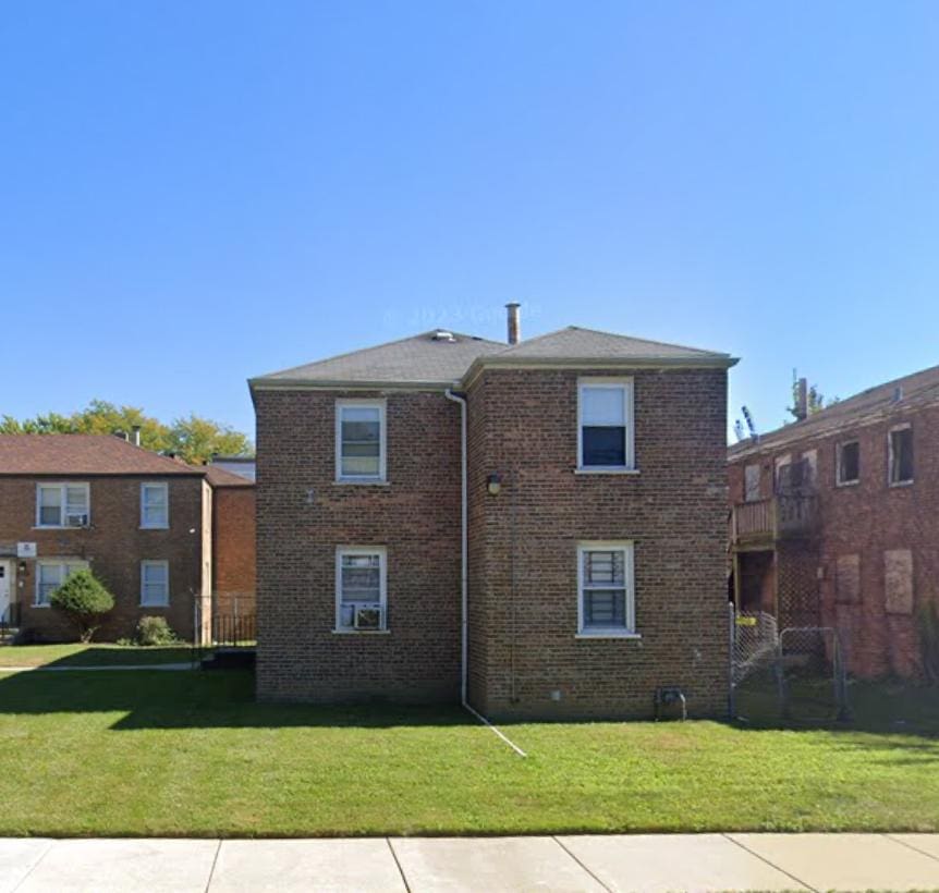 back of property featuring brick siding and a yard