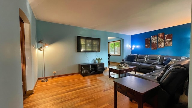 living area featuring arched walkways and light wood-style floors