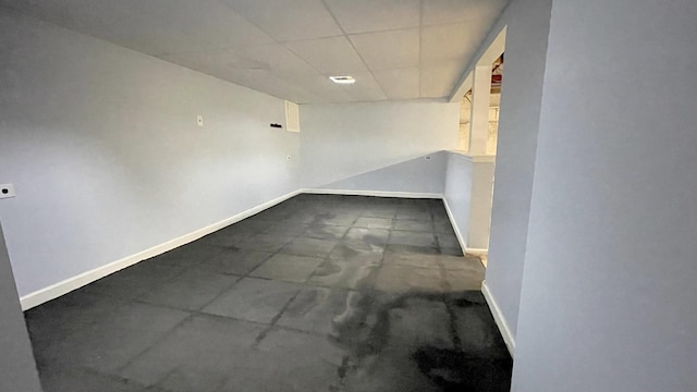 spare room featuring a drop ceiling and baseboards