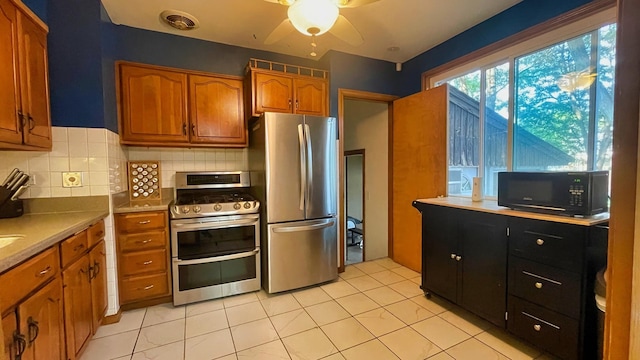 kitchen with stainless steel appliances, brown cabinets, ceiling fan, decorative backsplash, and light tile patterned floors