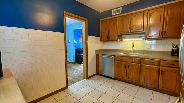 kitchen with dishwasher, brown cabinets, light tile patterned flooring, and tasteful backsplash