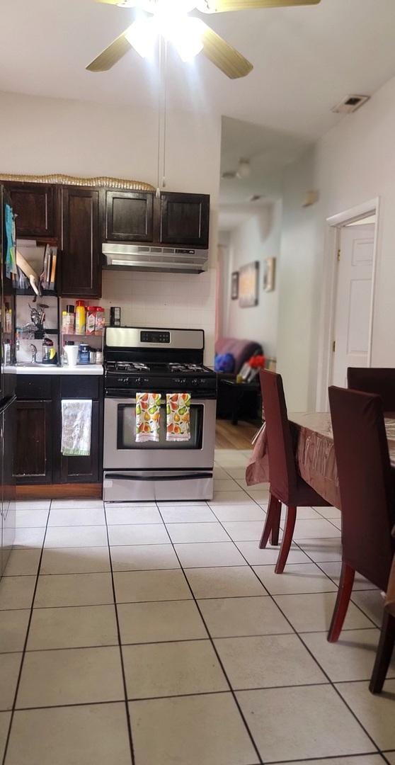 4751 S Hoyne Ave, Chicago, IL 60609 - kitchen featuring stainless steel range with gas stovetop, under cabinet range hood, light tile patterned floors, and ceiling fan