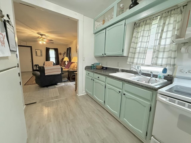 1229 W 6th St, Sterling, IL 61081 - kitchen featuring white range with electric stovetop, green cabinets, ceiling fan, a sink, and light wood-style floors