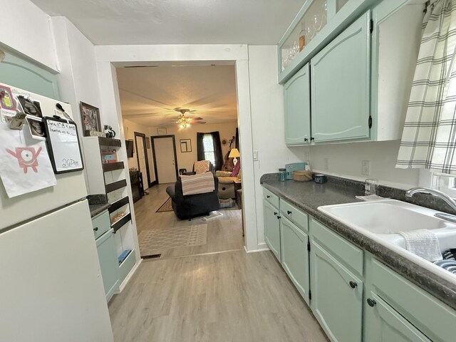 1229 W 6th St, Sterling, IL 61081 - kitchen featuring freestanding refrigerator, green cabinetry, light wood-type flooring, a sink, and a ceiling fan