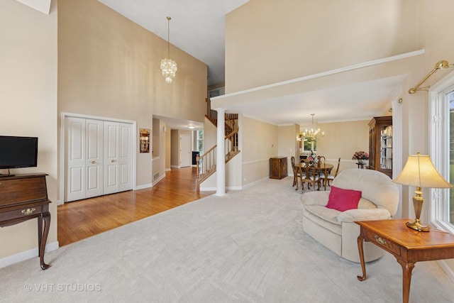 1051 Chadwick Ct, Aurora, IL 60502 - carpeted living room featuring a chandelier, a towering ceiling, stairs, ornamental molding, and wood finished floors
