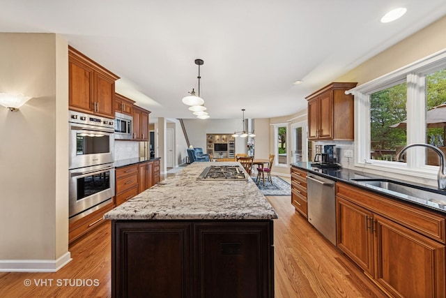 1051 Chadwick Ct, Aurora, IL 60502 - kitchen featuring appliances with stainless steel finishes, light wood-style floors, decorative backsplash, and a center island