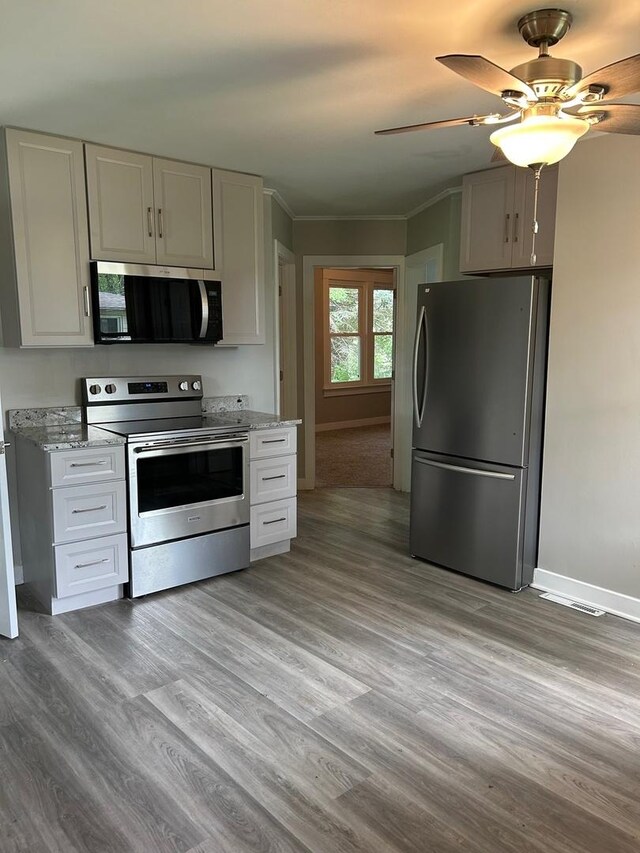904 Johnson St, Streator, IL 61364 - kitchen with stainless steel appliances, white cabinetry, light wood-style flooring, baseboards, and crown molding