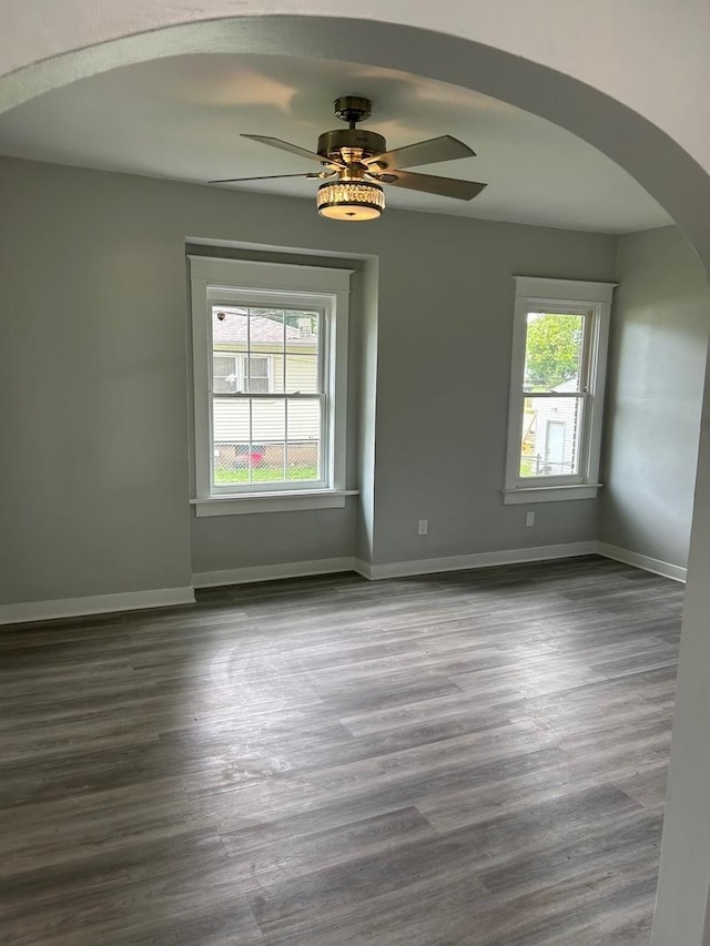 904 Johnson St, Streator, IL 61364 - unfurnished room featuring arched walkways, dark wood finished floors, ceiling fan, and baseboards