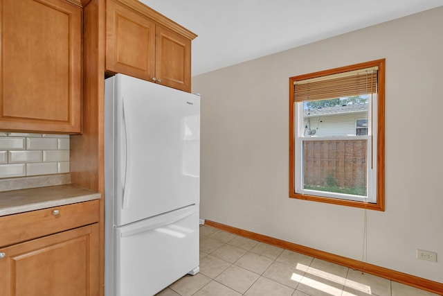 402 Kenyon Ave, Romeoville, IL 60446 - kitchen featuring freestanding refrigerator, decorative backsplash, light countertops, brown cabinets, and light tile patterned floors