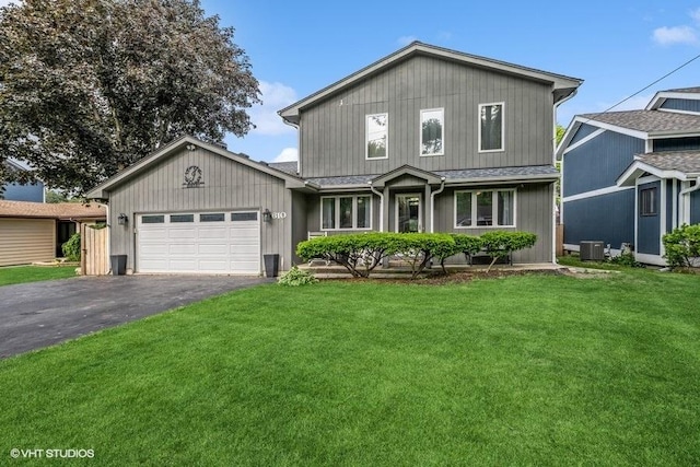 610 Mchenry Ave, Mchenry, IL 60050 - traditional-style home featuring asphalt driveway, an attached garage, central AC, a front yard, and a shingled roof