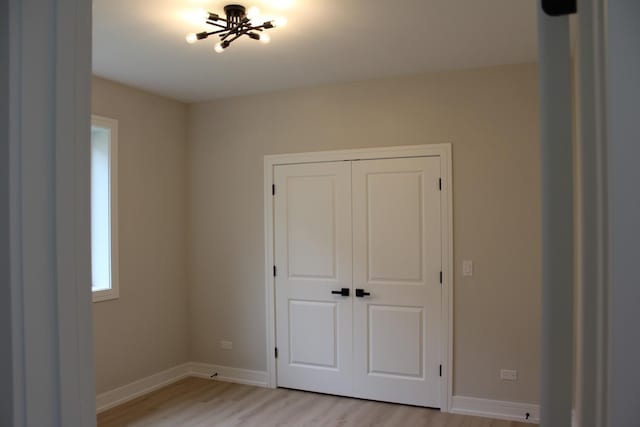 5660 W 83rd Pl, Burbank, IL 60459 - unfurnished bedroom featuring light wood-type flooring, baseboards, a closet, and a chandelier