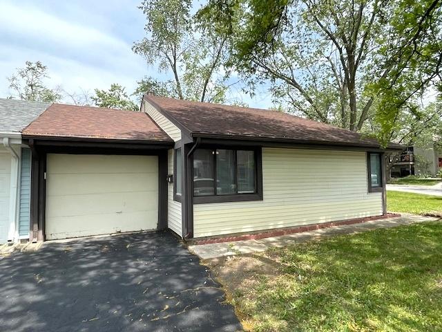 211 W Birchwood Dr Unit 211, Romeoville, IL 60446 - view of property exterior featuring a garage, driveway, and roof with shingles