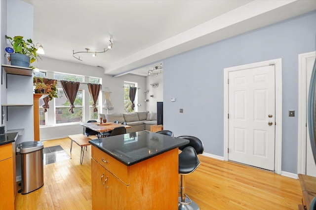2744 W Haddon Ave Unit 2, Chicago, IL 60622 - kitchen with a kitchen island, dark countertops, light wood finished floors, a kitchen breakfast bar, and brown cabinets
