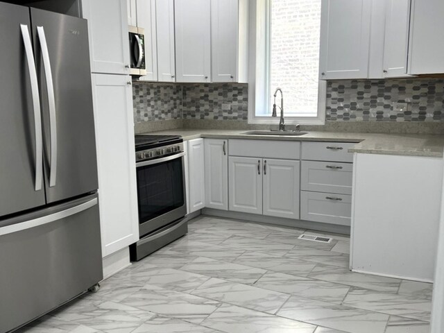 2627 E 74th Pl, Chicago, IL 60649 - kitchen featuring stainless steel appliances, a sink, light marble finish floors, light countertops, and backsplash
