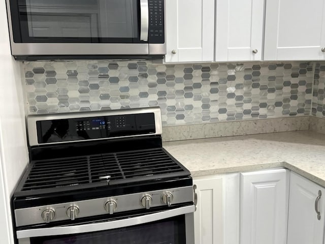 2627 E 74th Pl, Chicago, IL 60649 - kitchen view of appliances with stainless steel finishes, decorative backsplash, and white cabinetry