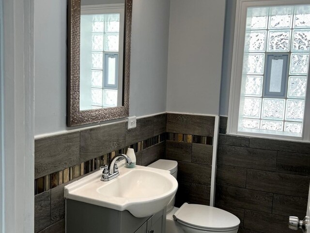 2627 E 74th Pl, Chicago, IL 60649 - bathroom featuring toilet, tile walls, vanity, and wainscoting