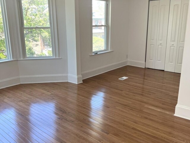 2627 E 74th Pl, Chicago, IL 60649 - unfurnished bedroom with hardwood / wood-style floors, multiple windows, and baseboards