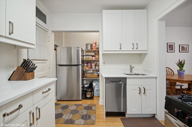2017 W Farragut Ave Unit 1, Chicago, IL 60625 - kitchen featuring appliances with stainless steel finishes, light countertops, light wood finished floors, and white cabinetry
